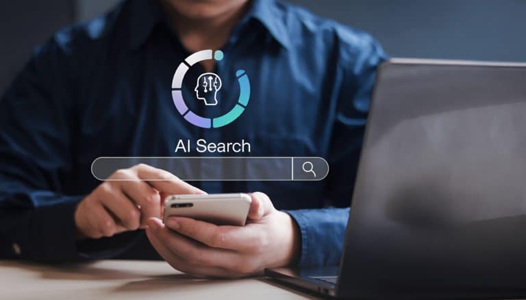 Professional realitzant una cerca des del mòbil mentre treballa en portàtil, il·lustrant com aconseguir que la IA citi la teva marca en entorns digitals.